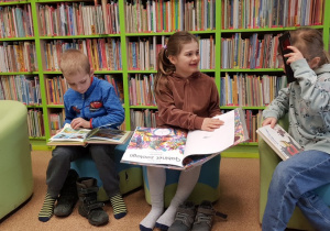 Dzieci siedzą na pufach i czytają książi